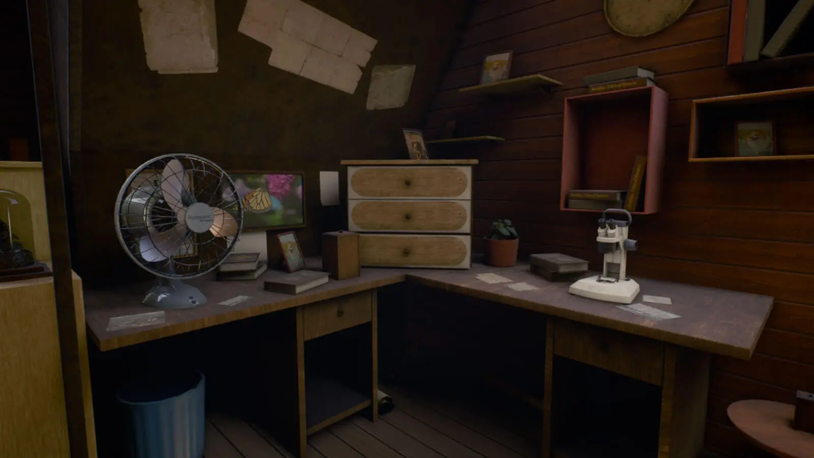 An old metal fan sits on a wooden desk with other objects on it