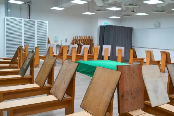 Students at a long table model human figures with gray clay based on miniature skeleton models standing between them.