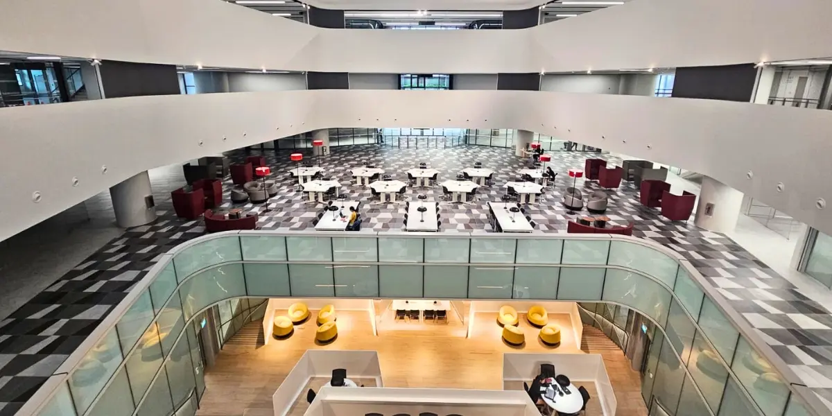 A woman looks intently at the modeling clay in her hands as she uses a metal implement to sculpt a human body.