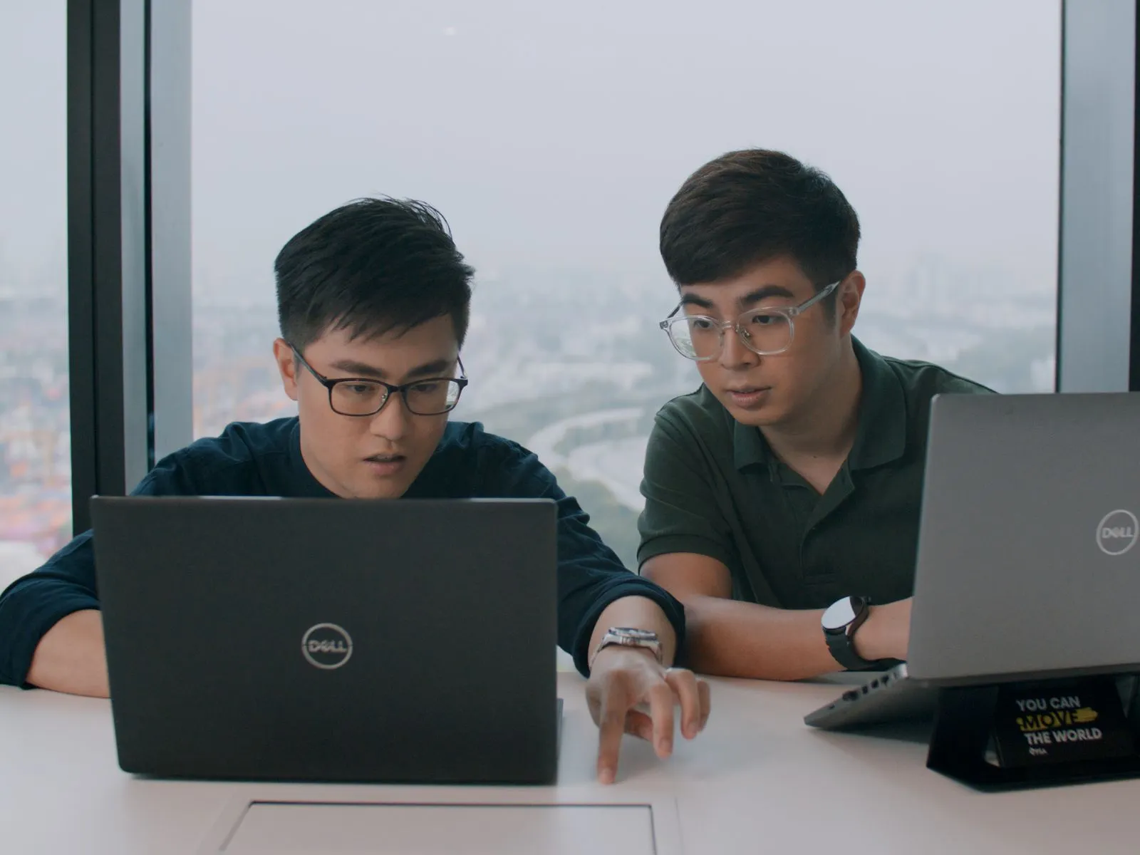 Alumni Justine Kee and Zachary Lee sit at a conference table and work on laptops.