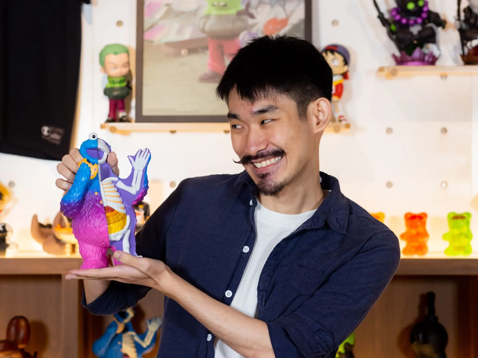 Alumni Ian Ng smiling as he holds up a Cookie Monster toy figure.