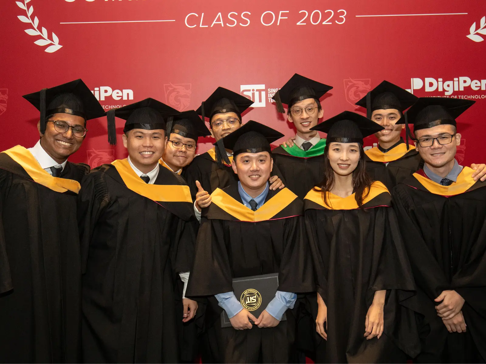 Several graduates of DigiPen smiling while dressed in a cap and gown.