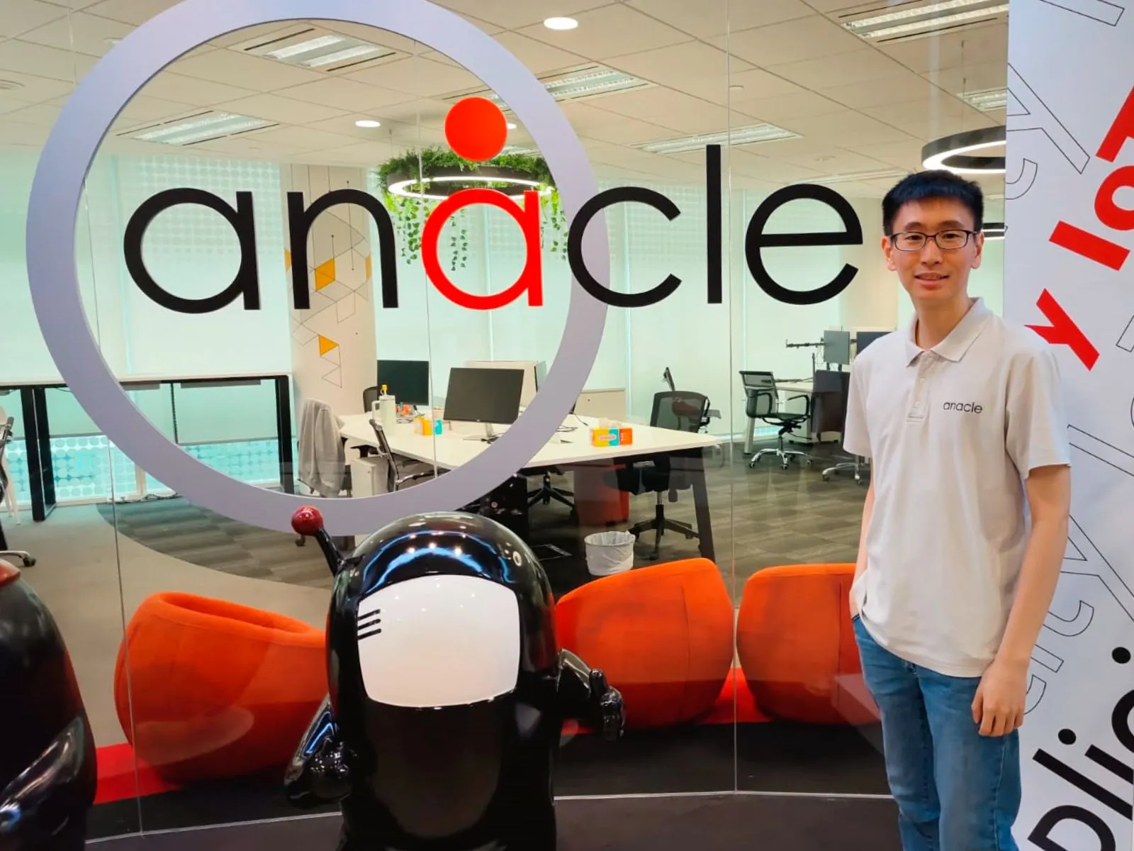 DigiPen graduate, Mok Wen Jie, stands in front of an Anacle Systems logo.