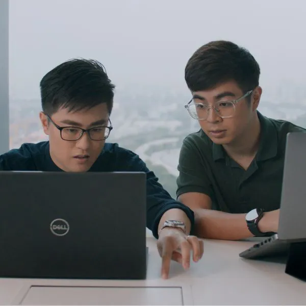 Alumni Justine Kee and Zachary Lee sit at a conference table and work on laptops.