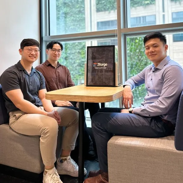 Three digipen singapore alumni sit at a table behind a 3forge logo.