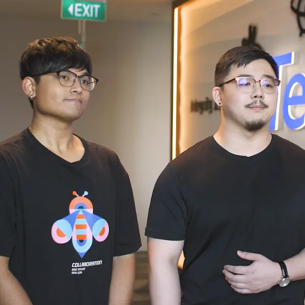 Alumni Gordon Christian and Hoo Xin Jie stand together in front of a Tencent logo.