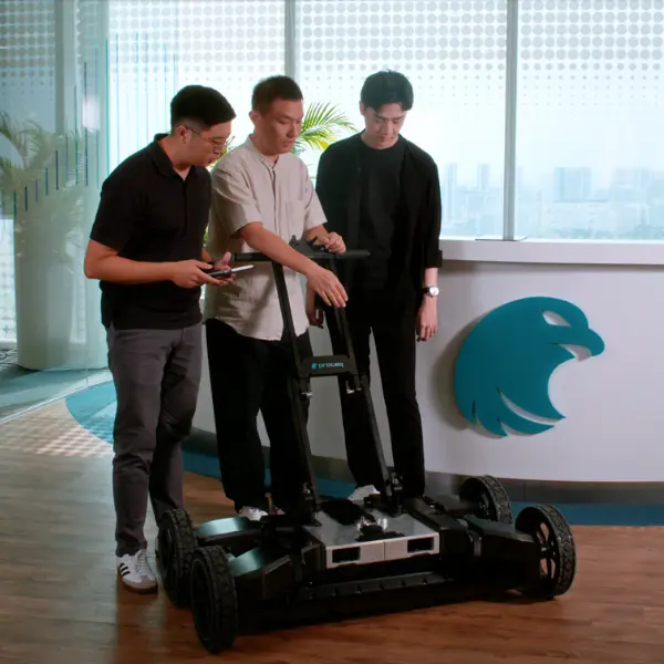 A group of men stand around a large robot with wheels.