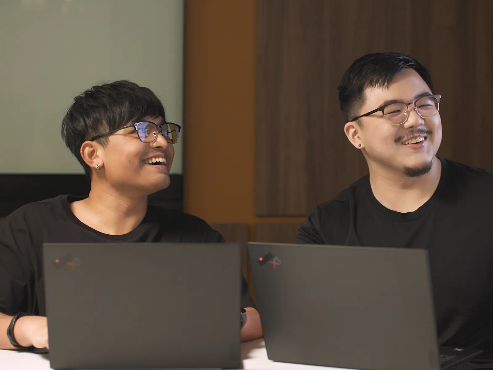 "Two DigiPen Singapore alumni smile while working on laptops"