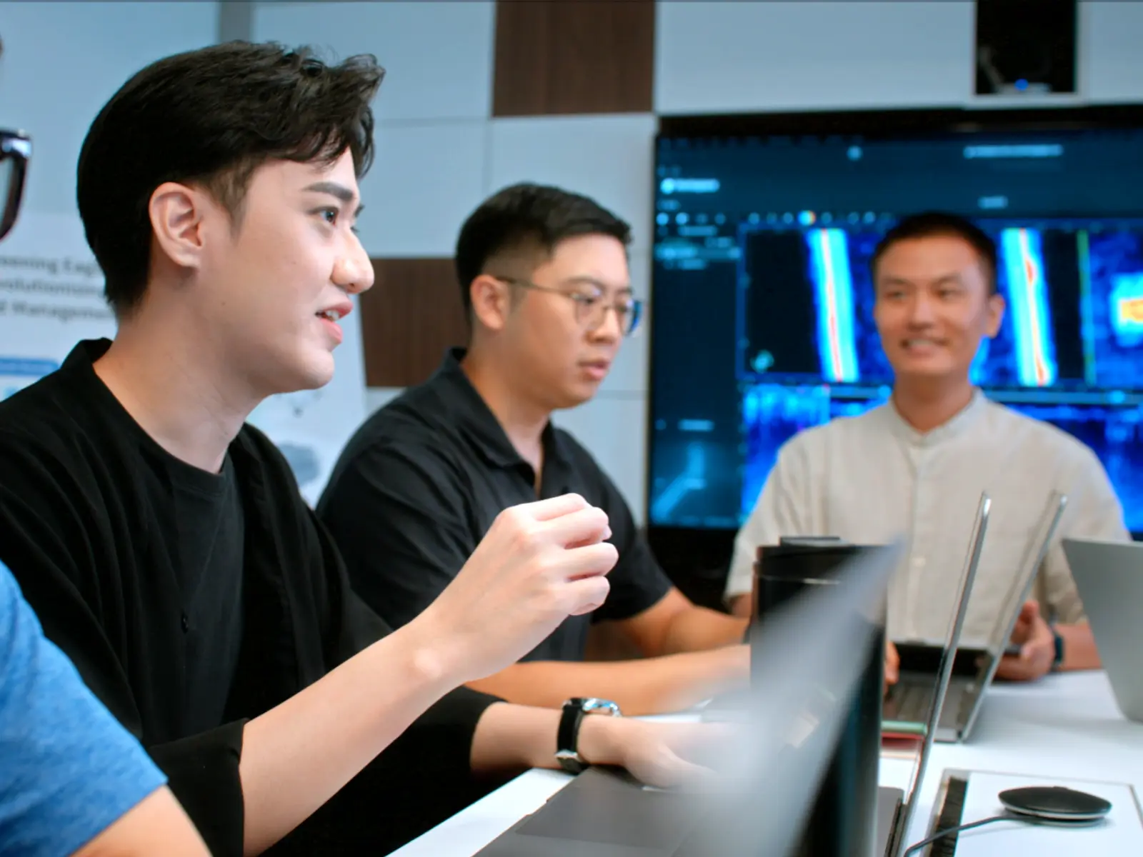 "A group of men work on laptops while in a conference."